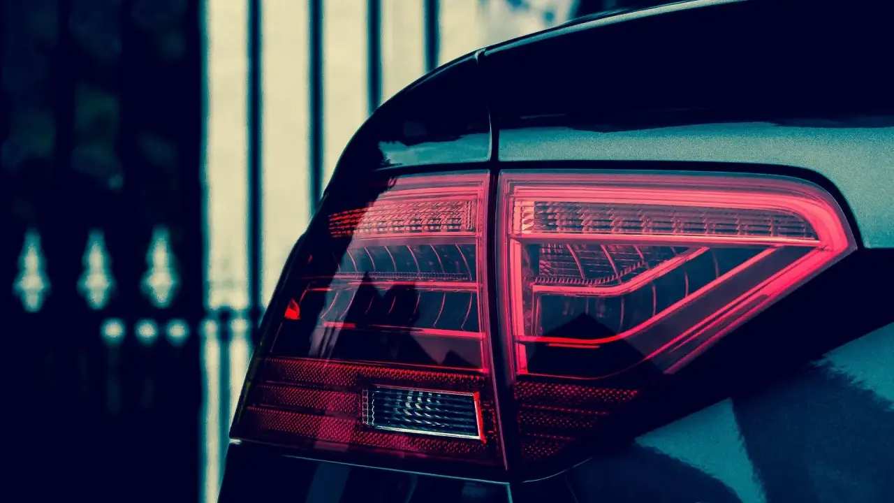 Czerwone światło tylne samochodu Audi A5, z widocznym napisem A5. Polimocznikowa obudowa lampy lśni w ciemności.