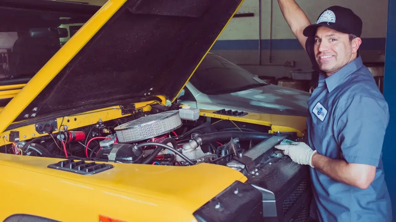 Mechanik sprawdza uszczelniacze zaworowe w żółtym samochodzie terenowym.