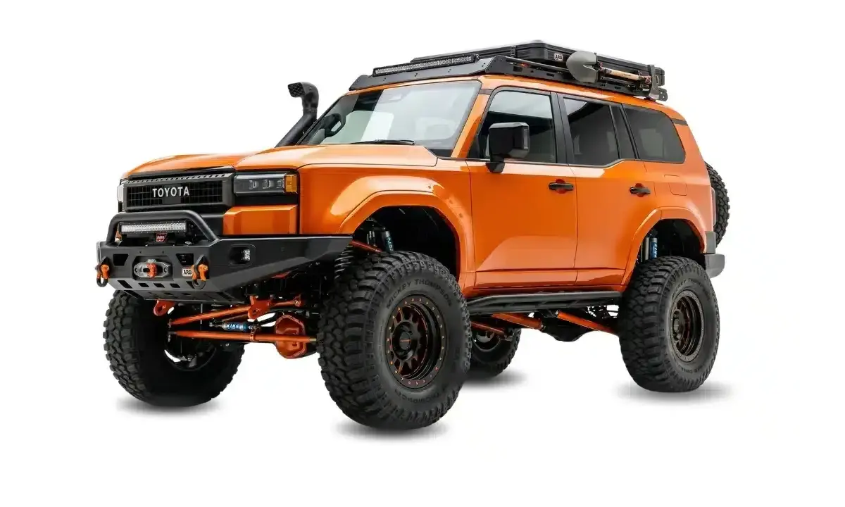 Pomarańczowy Toyota z terenowym wyposażeniem, wyciągarką i bagażnikiem dachowym. Zastanawiasz się, ile kosztuje malowanie auta Raptor?
