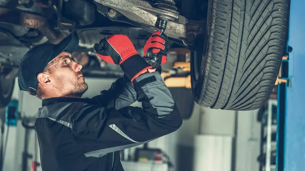 Mechanik dokręca sworznie wahaczy, dbając o bezpieczeństwo jazdy.
