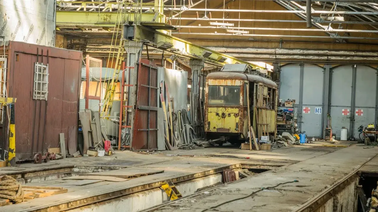 Zardzewiały tramwaj w zajezdni, gotowy na przegląd. Brak przeglądu grozi mandatem.