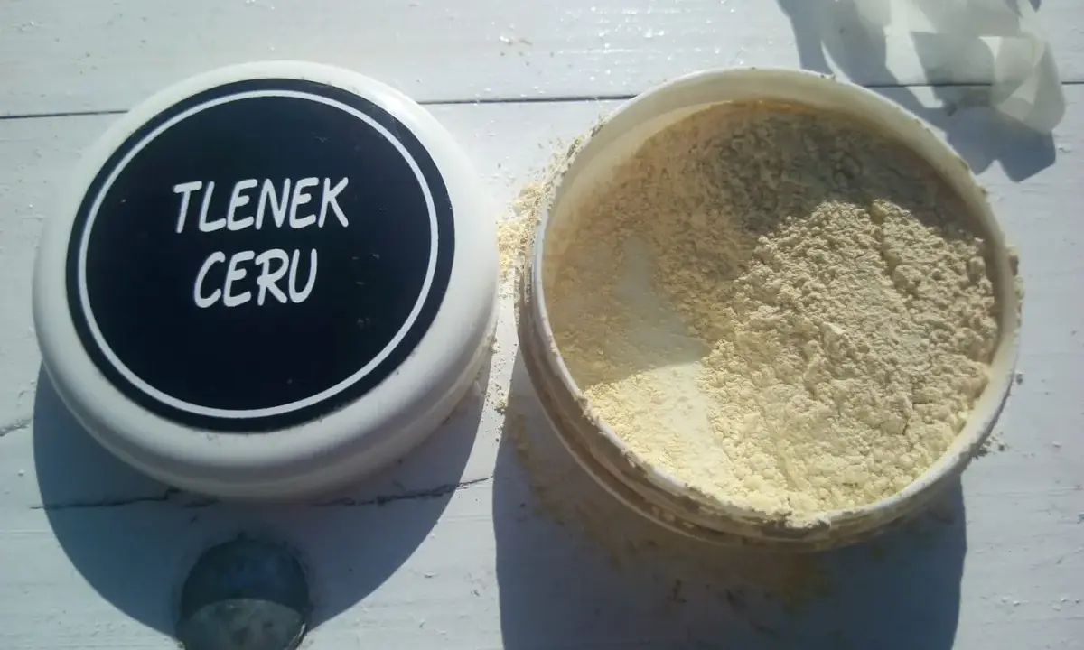 Otwarty pojemnik z jasnym proszkiem, na wieczku napis "TLENEK CERU".