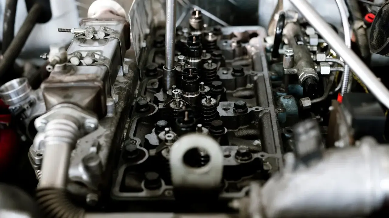 Widok wnętrza silnika z widocznymi zaworami i sprężynami. Widać fragmenty układu paliwowego i metalowe elementy, które są częścią mechanizmu, gdzie pracują tłoki.