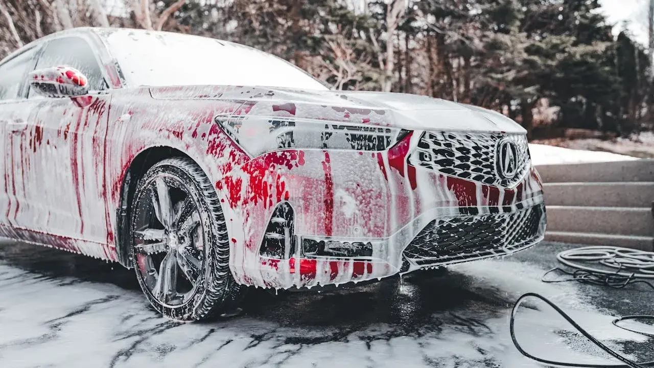 Czerwony samochód pokryty pianą, gotowy do mycia. Czy można myć auto w mrozie? To pytanie zadaje sobie wielu kierowców zimą.
