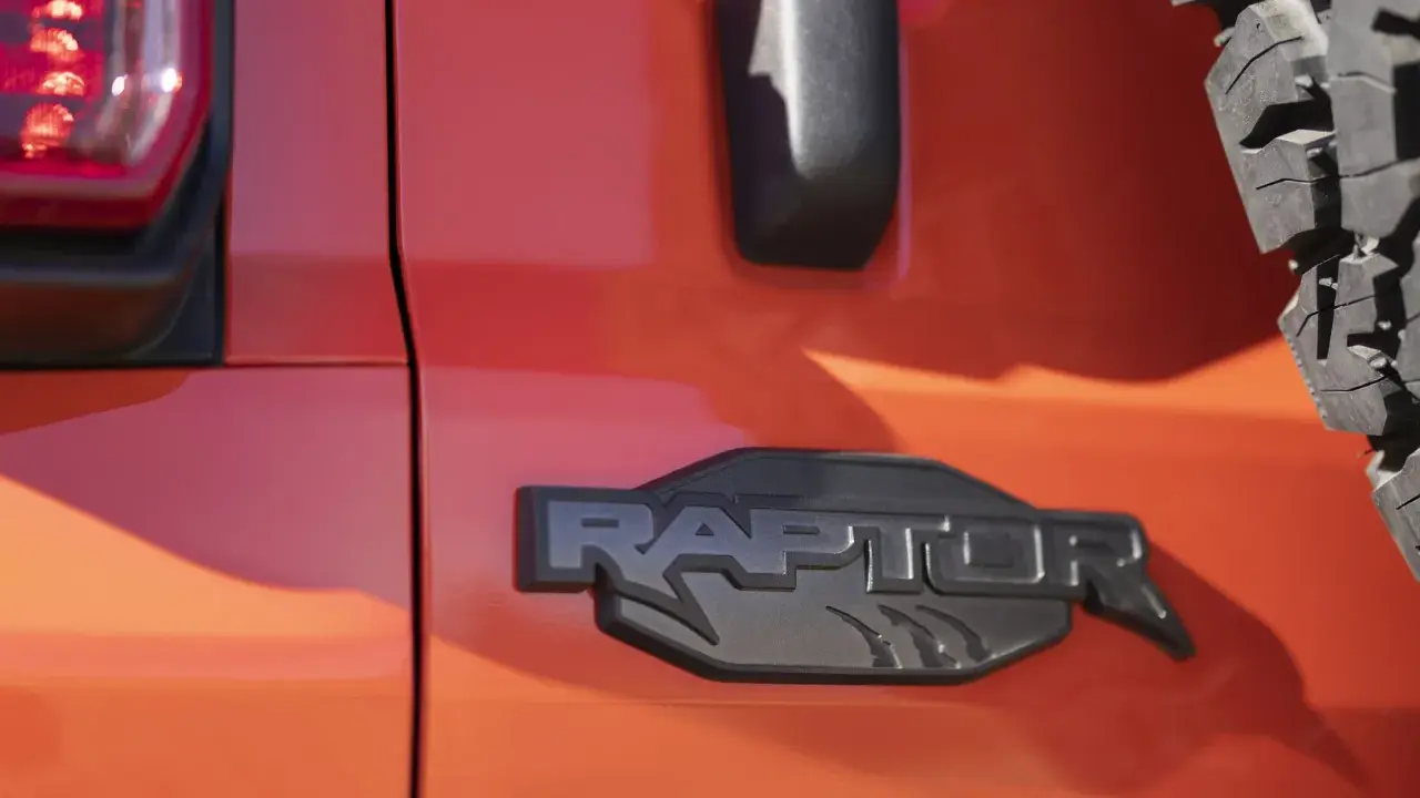 Pomarańczowy lakier lśni, a czarne, wyraziste logo "RAPTOR" z pazurami podkreśla jego dziką naturę.