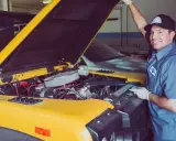 Mechanik sprawdza uszczelniacze zaworowe w żółtym samochodzie terenowym.
