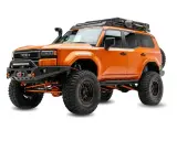 Pomarańczowy Toyota z terenowym wyposażeniem, wyciągarką i bagażnikiem dachowym. Zastanawiasz się, ile kosztuje malowanie auta Raptor?