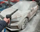 Jak myć auto na myjni: piana pokrywa samochód, a ręka trzyma pistolet ciśnieniowy.