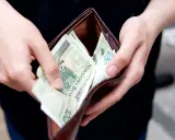 Ręce trzymają portfel z polskimi banknotami. Zastanawiasz się, ile kosztuje przegląd samochodu z gazem?