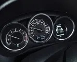 Deska rozdzielcza z obrotomierzem, prędkościomierzem i wyświetlaczem i-ELOOP. Widać falujące obroty silnika i prędkość 100 km/h.