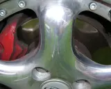 Błyszczące polerowanie aluminium felgi z widocznym czerwonym zaciskiem hamulcowym i tarczą.