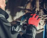 Mechanik w czerwonych rękawicach pracuje nad układem hamulcowym, przygotowując wymianę przewodów hamulcowych.
