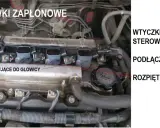Silnik samochodowy z widocznymi cewkami zapłonowymi, śrubami mocującymi do głowicy i wtyczkami od sterownika.