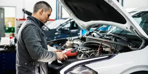 Mechanik sprawdza stan akumulatora, przygotowując samochód do przeglądu. Opłata za przegląd samochodu obejmuje takie diagnostyki.