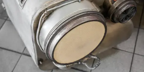 Element układu wydechowego, prawdopodobnie filtr DPF, gotowy do wypalania. Widoczny ceramiczny wkład.