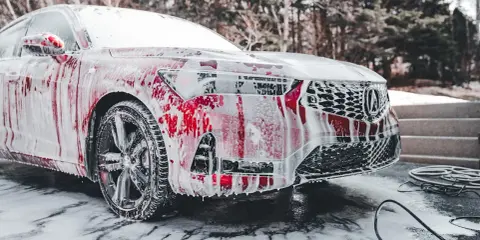 Czerwony samochód pokryty pianą, gotowy do mycia. Czy można myć auto w mrozie? To pytanie zadaje sobie wielu kierowców zimą.