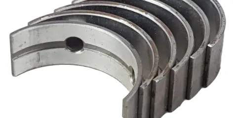 Kilka metalowych panewek Kolbenschmidt, gotowych do montażu w silniku.
