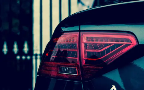 Czerwone światło tylne samochodu Audi A5, z widocznym napisem A5. Polimocznikowa obudowa lampy lśni w ciemności.