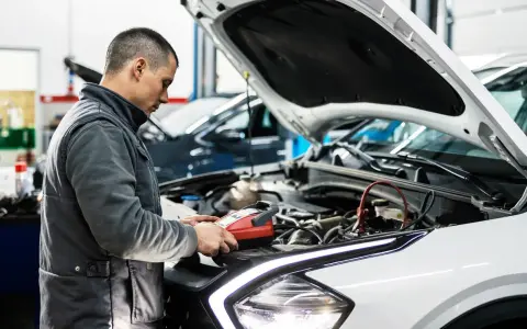 Mechanik sprawdza stan akumulatora, przygotowując samochód do przeglądu. Opłata za przegląd samochodu obejmuje takie diagnostyki.