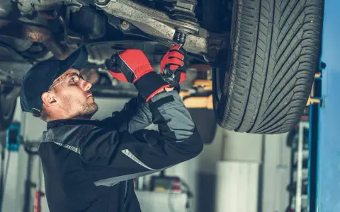 Mechanik dokręca sworznie wahaczy, dbając o bezpieczeństwo jazdy.
