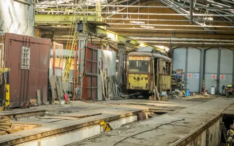 Zardzewiały tramwaj w zajezdni, gotowy na przegląd. Brak przeglądu grozi mandatem.