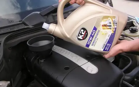 Wlewanie oleju silnikowego K2 10W-40 do silnika Mercedesa. Różne rodzaje olejów silnikowych są kluczowe dla jego pracy.