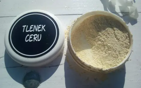 Otwarty pojemnik z jasnym proszkiem, na wieczku napis "TLENEK CERU".