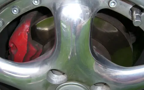 Błyszczące polerowanie aluminium felgi z widocznym czerwonym zaciskiem hamulcowym i tarczą.