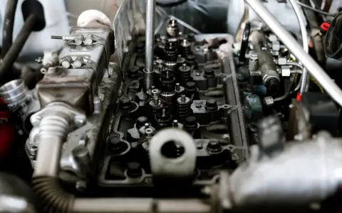 Widok wnętrza silnika z widocznymi zaworami i sprężynami. Widać fragmenty układu paliwowego i metalowe elementy, które są częścią mechanizmu, gdzie pracują tłoki.