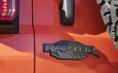 Pomarańczowy lakier lśni, a czarne, wyraziste logo "RAPTOR" z pazurami podkreśla jego dziką naturę.