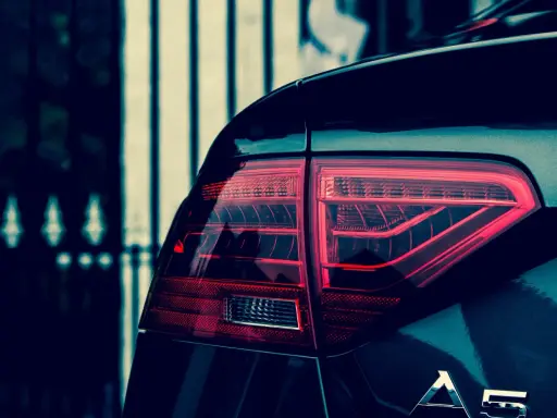 Czerwone światło tylne samochodu Audi A5, z widocznym napisem A5. Polimocznikowa obudowa lampy lśni w ciemności.