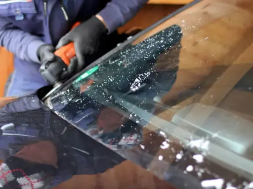 Naprawa odprysku na szybie samochodu. Ręce w rękawiczkach trzymają narzędzie, które usuwa uszkodzenie.