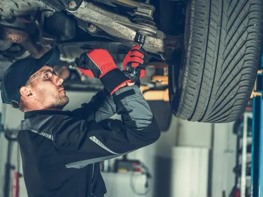 Mechanik dokręca sworznie wahaczy, dbając o bezpieczeństwo jazdy.