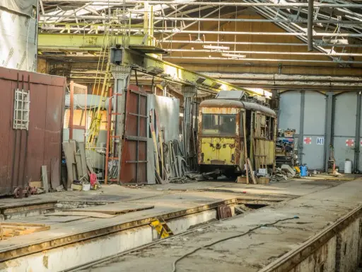 Zardzewiały tramwaj w zajezdni, gotowy na przegląd. Brak przeglądu grozi mandatem.