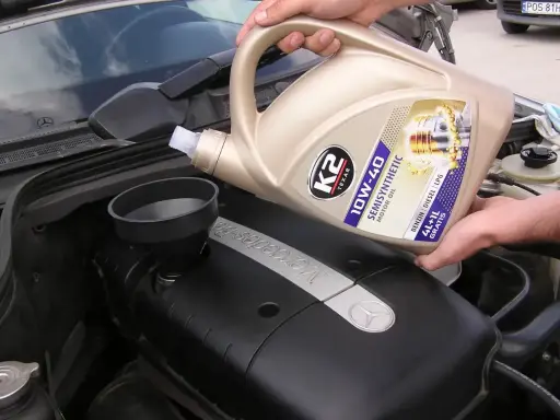 Wlewanie oleju silnikowego K2 10W-40 do silnika Mercedesa. Różne rodzaje olejów silnikowych są kluczowe dla jego pracy.
