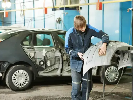 Pracownik szlifuje zderzak przed lakierowaniem. Czas potrzebny na lakierowanie zderzaka zależy od wielu czynników.