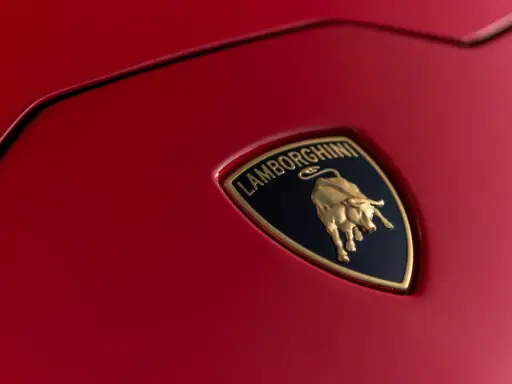 Złoty byk na czarnym tle z napisem "Lamborghini" - tak wygląda znaczek tej marki na czerwonej karoserii.