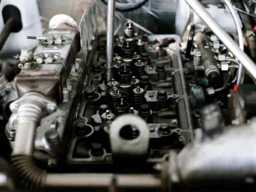 Widok wnętrza silnika z widocznymi zaworami i sprężynami. Widać fragmenty układu paliwowego i metalowe elementy, które są częścią mechanizmu, gdzie pracują tłoki.