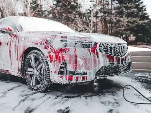 Czerwony samochód pokryty pianą, gotowy do mycia. Czy można myć auto w mrozie? To pytanie zadaje sobie wielu kierowców zimą.