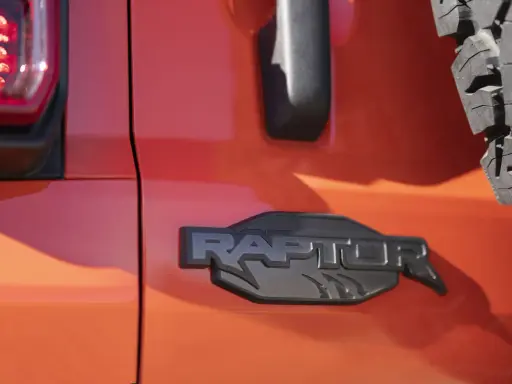 Pomarańczowy lakier lśni, a czarne, wyraziste logo "RAPTOR" z pazurami podkreśla jego dziką naturę.