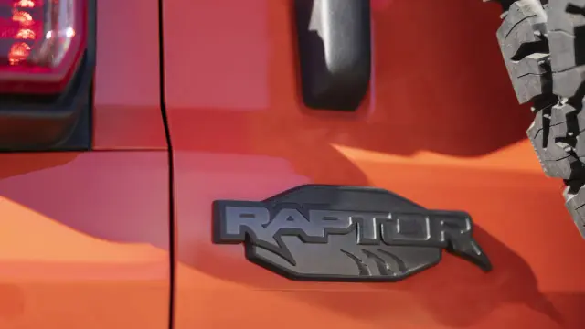 Pomarańczowy lakier lśni, a czarne, wyraziste logo "RAPTOR" z pazurami podkreśla jego dziką naturę.