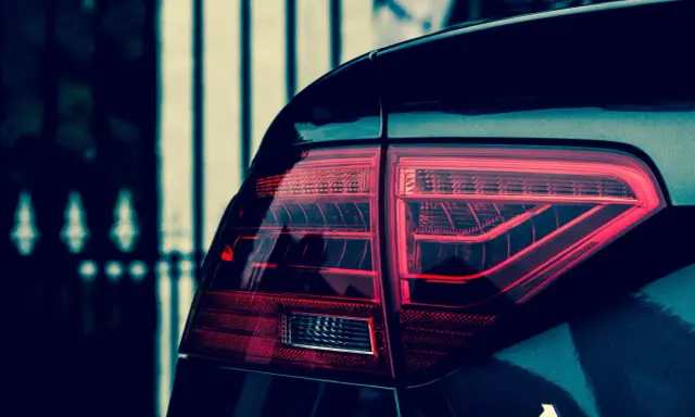 Czerwone światło tylne samochodu Audi A5, z widocznym napisem A5. Polimocznikowa obudowa lampy lśni w ciemności.
