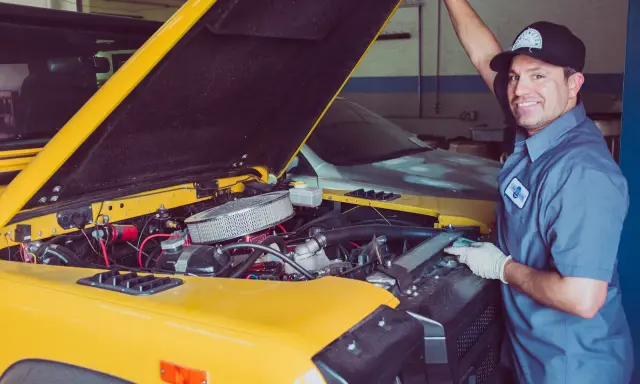 Mechanik sprawdza uszczelniacze zaworowe w żółtym samochodzie terenowym.