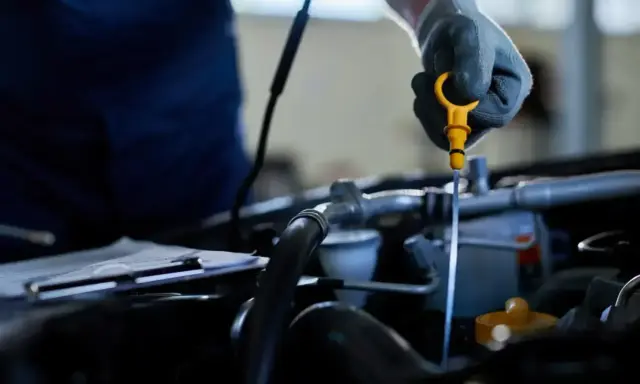 Mechanik sprawdza poziom oleju, co może pomóc wykryć nieszczelna odma objawy.