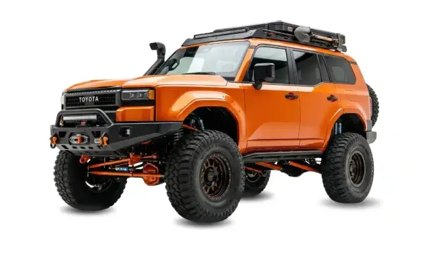 Pomarańczowy Toyota z terenowym wyposażeniem, wyciągarką i bagażnikiem dachowym. Zastanawiasz się, ile kosztuje malowanie auta Raptor?