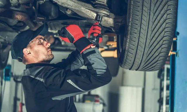 Mechanik dokręca sworznie wahaczy, dbając o bezpieczeństwo jazdy.