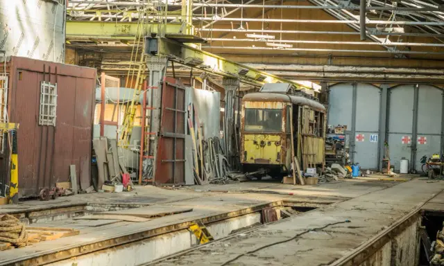 Zardzewiały tramwaj w zajezdni, gotowy na przegląd. Brak przeglądu grozi mandatem.