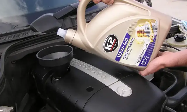 Wlewanie oleju silnikowego K2 10W-40 do silnika Mercedesa. Różne rodzaje olejów silnikowych są kluczowe dla jego pracy.