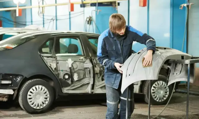 Pracownik szlifuje zderzak przed lakierowaniem. Czas potrzebny na lakierowanie zderzaka zależy od wielu czynników.