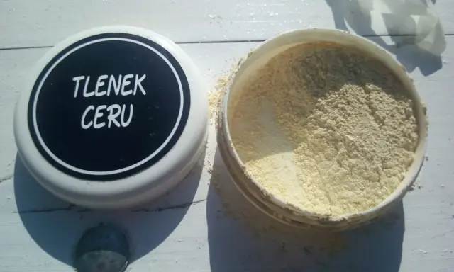 Otwarty pojemnik z jasnym proszkiem, na wieczku napis "TLENEK CERU".